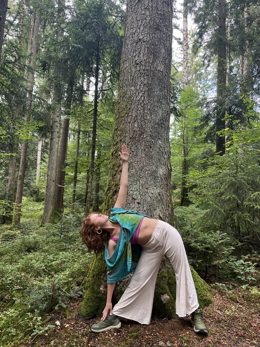 Jazmin en postura del triángulo junto a un árbol